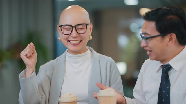 Two people smile warmly while holding coffee cups. They appear engaged, sharing a friendly, supportive moment
