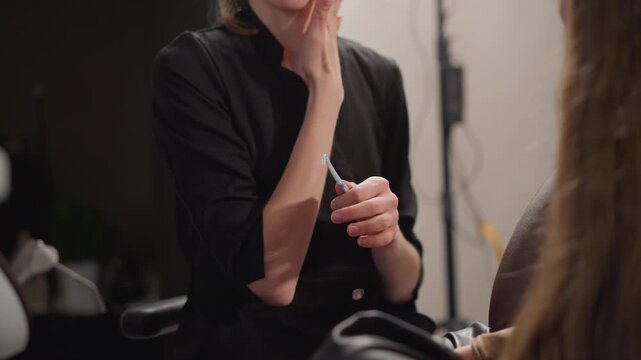 Close up of woman applying dental care product to another woman teeth in indoor setting. subject holds and uses tool demonstrating proper technique with steady hands while interacting