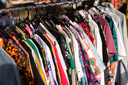 Clothing rack filled with colourful shirts and tops hanging neatly on black hangers