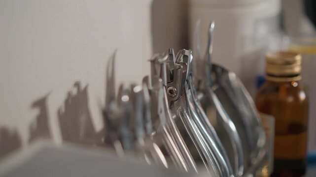 Close up of various metal orthodontic tools arranged on white surface in soft lighting. scene includes shiny metallic instruments with distinct shapes and sizes alongside blurred background