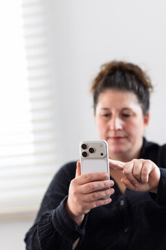 Close up of woman holding smart phone and tapping screen indoors