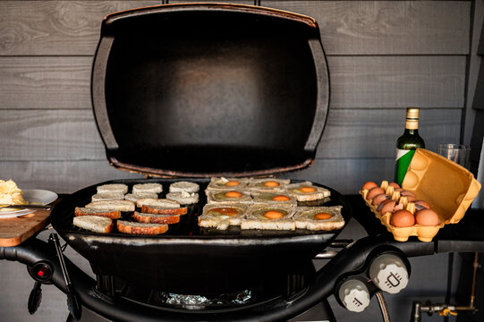Preparing traditional toad in a hole for breakfast on a barbecue with eggs and bread in Crackenback