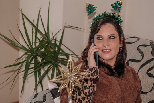 Young happy woman using smartphone at home on Christmas