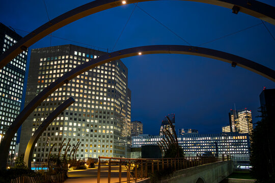 Modern office architecture with curved arches in Paris photographed at blue hour with illuminated buildings seen through the curved office structure