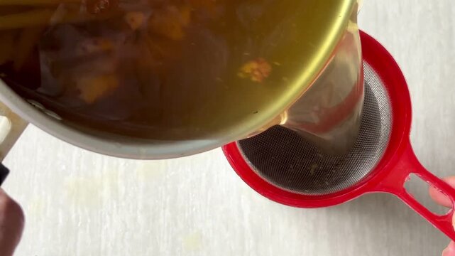 A traditional herbal decoction&mdash;strained to create a healthful beverage from a blend of spices such as red ginger, galangal, turmeric, and lemongrass&mdash;being poured into a blue glass.