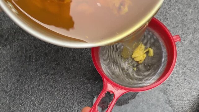 A traditional herbal decoction&mdash;strained to create a healthful beverage from a blend of spices such as red ginger, galangal, turmeric, and lemongrass&mdash;being poured into a blue glass.