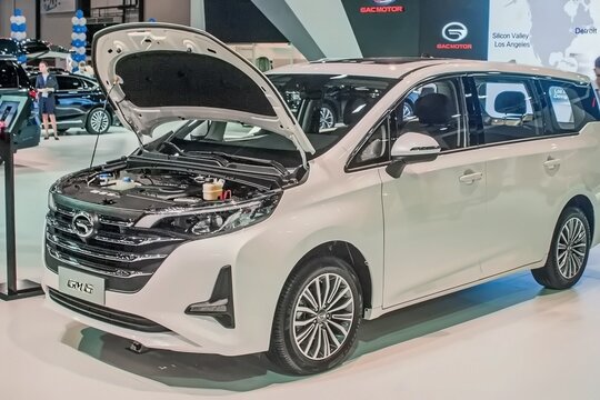 White minivan GAC Trumpchi GM6 with an open hood is showcased at a car exhibition. The vehicle features a modern design with shiny details, parked indoors under bright lights - April 06, 2019, Russia