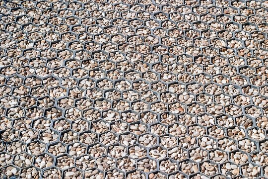 Road surface of small stones set in hexagonal cells, paving pattern with geometric texture