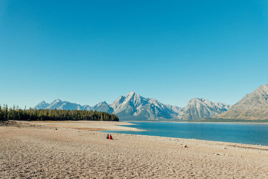 A wide exposed beach borders a receded mountain lake.