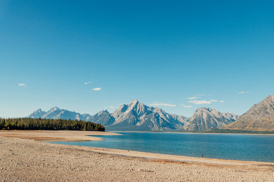 Receded water reveals exposed shoreline beneath rugged mountains.