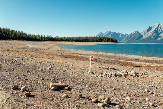 Swimming area marker post exposed on receded shoreline.