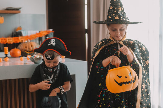 Medium shot of children in Halloween costumes looking for treats in pumpkin-shaped baskets. Trick or treat. Celebrating Halloween with children and collecting candy.
