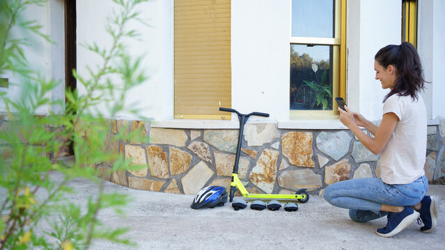 Woman taking picture of scooter and protective gear for selling online