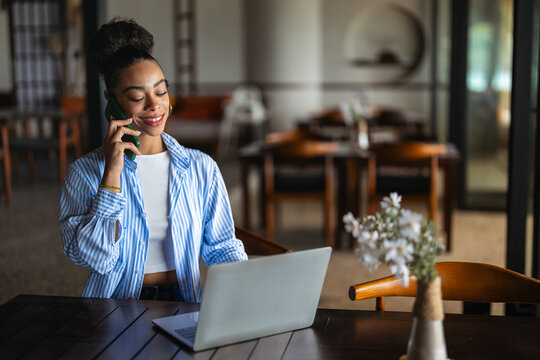 Woman entrepreneur managing her business from remote work. Working on laptop in restaurant