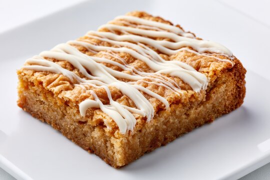 A delicious square blondie dessert bar drizzled with white chocolate icing, isolated on white background