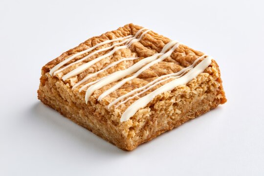 A delicious square blondie dessert bar drizzled with white chocolate icing, isolated on white background