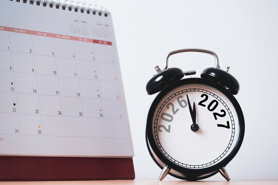 2026 to 2027 New Year transition concept featuring a black alarm clock beside a desk calendar symbolizing year end countdown and preparation new year for future planing time management.