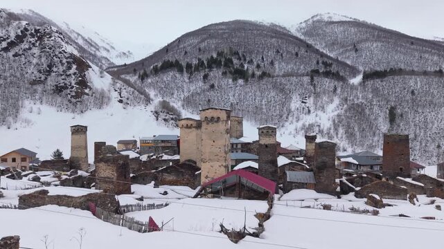 Aerial footage circling one of the five villages that form Ushguli, showcasing medieval stone houses, Svan towers, and the spectacular snow-covered Caucasus landscape in Georgia.