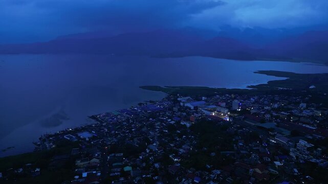 Cinematic aerial view of Buhi town and Lake Buhi during blue hour in Camarines Sur, Philippines. The footage features the urban and lakeside areas around San Benito, San Pascual and Santa Cruz, with M