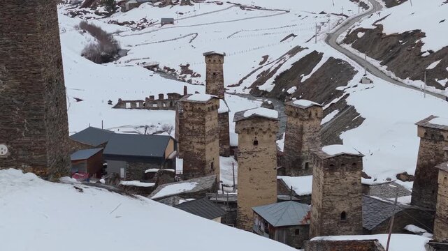 Drone footage pulling back from one Ushguli settlement to unveil another neighboring community, showcasing the layered winter landscape and historic Svaneti villages in Georgia.