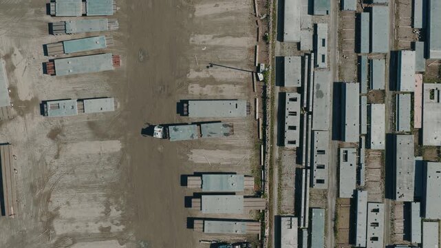 Precast concrete plant storage yard, with wall panels and hollow-core slabs resting on timber dunnage in long parallel rows across bare ground.