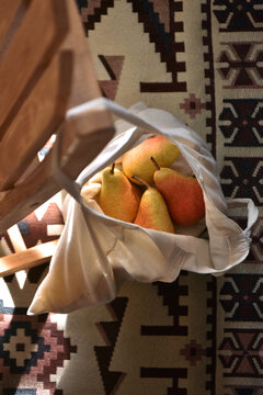 Fresh pears in a grocery bag hanging on a wooden chair