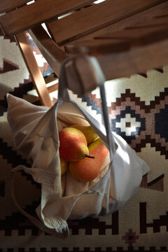 Fresh pears in a cotton grocery bag hanging on the chair in a rustic cozy home with the traditional kilim rug