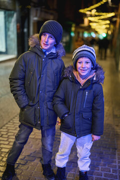 Two boys together on illuminated city street at night