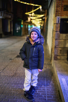 Boy standing on illuminated city street at night