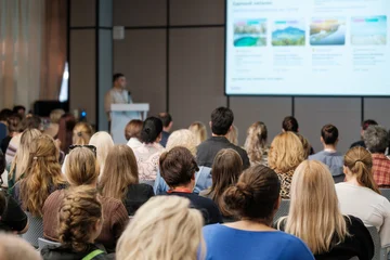 Tourism seminar attendees face projected destination photographs during an indoor presentation. © Anton Gvozdikov