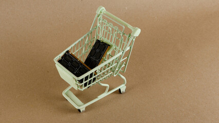 Random access memory modules resting inside a tiny shopping cart on a brown surface, symbolizing hardware procurement, technology investment, and upgrading digital processing power © Dark Artistic