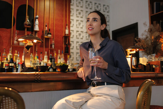 Young businesswoman drinks wine at the hotel bar in the evening