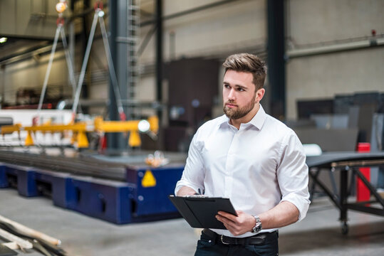 Male engineer holds a clipboard in a production facility
