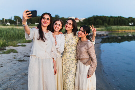 Happy female friends take a summer selfie on the beach