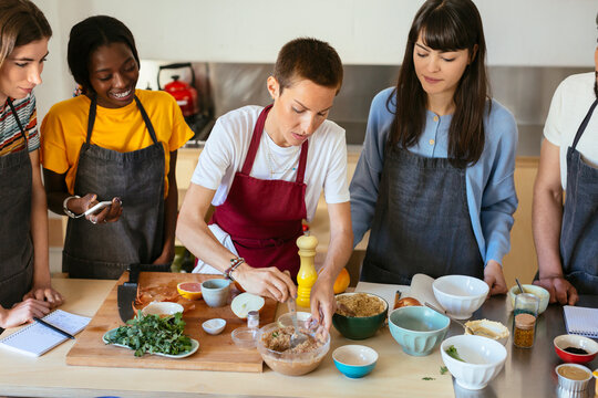 Friends and instructor in a cooking workshop preparing food