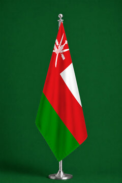3D illustration. Flag of Oman on a ceremonial standing flag on a pole with a metal base.