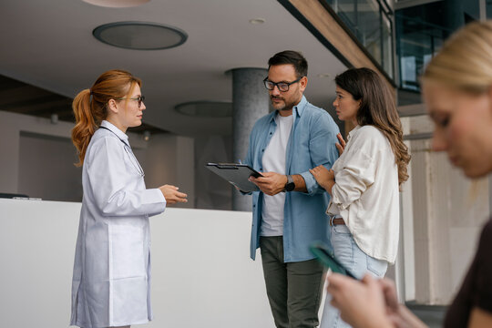 Doctor consulting with patients during form filling at hospital reception
