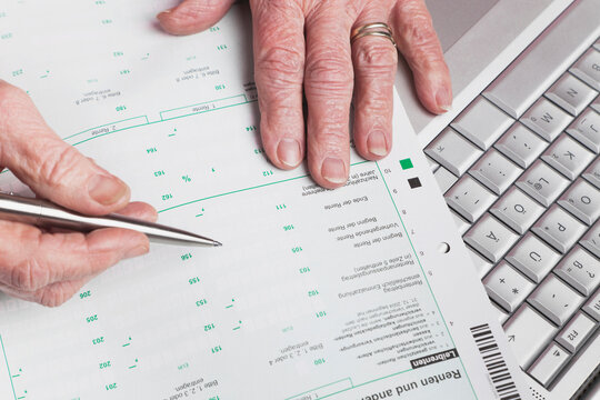 Germany, Senior woman with pension statement and laptop