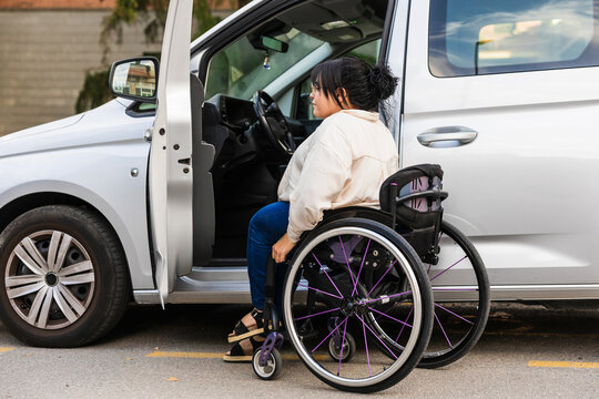 Woman in wheelchair preparing to enter adapted car outdoors