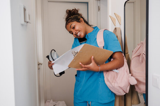 Caregiver nurse assistant multitasking at home with clipboard and phone