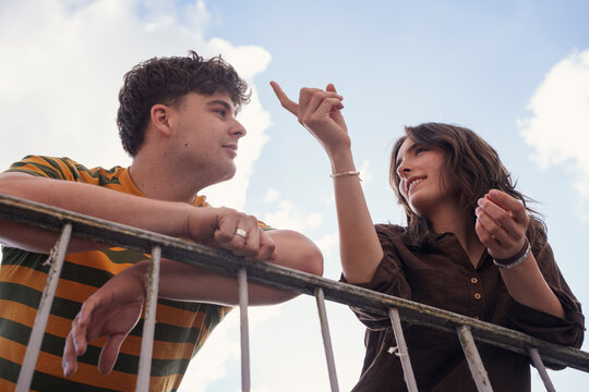 Friends talk and point at the sky on a balcony