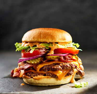 A delicious double smashburger sits on a dark table in sunlight