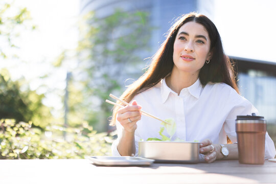 Businesswoman eats healthy homemade food during outdoor lunch break
