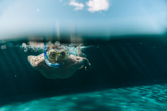 Man with diving goggles and snorkel underwater in a swimming pool