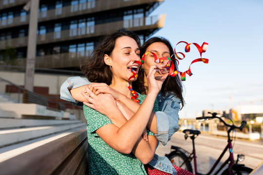 Woman hugging friend and blowing streamers outdoors in Hamburg