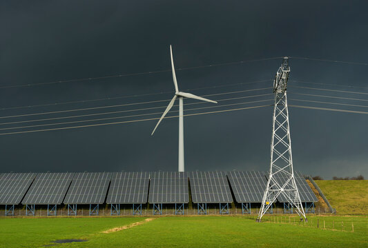 Solar panels and wind turbine on landfill with power lines in the Netherlands