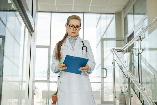 Female doctor reads a medical document on a clipboard in the hospital