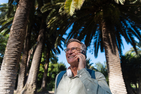 Smiling man talks on smartphone at Ciutadella Park in Barcelona