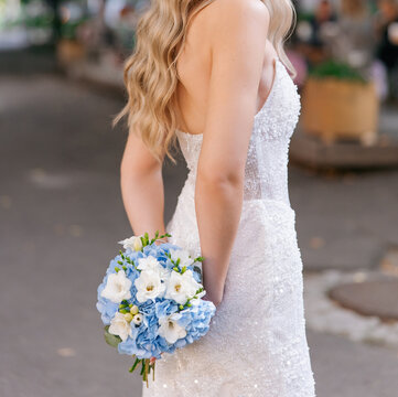 Bride holding wedding blue and white bouquet behind back