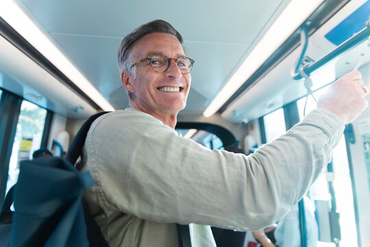 A smiling man holds a handrail while commuting on a tram in Barcelona